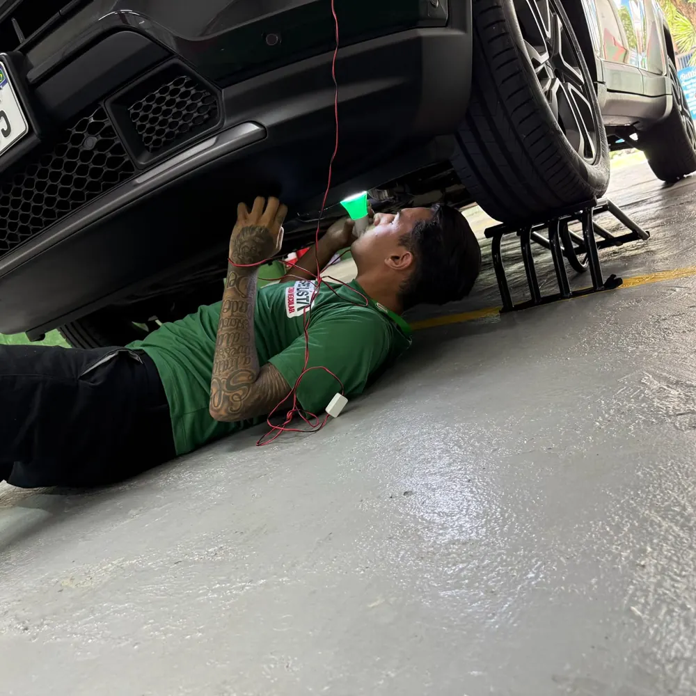 Vistoriador inspecionando a parte de baixo do veículo